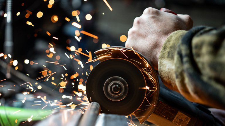 Close-up of angle grinder cutting metal with sparks, showcasing skilled trades and metalworking processes in manufacturing.