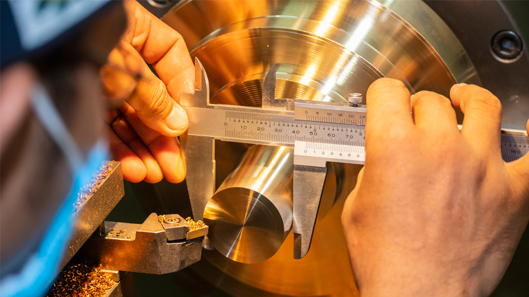 a steady hand measures a 3d printed shaft with a pair of calipers